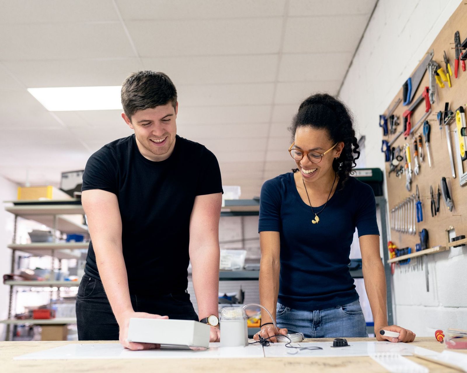 Business owner and senior team member leaning over a workbench in their workshop, planning the next stage of the business together