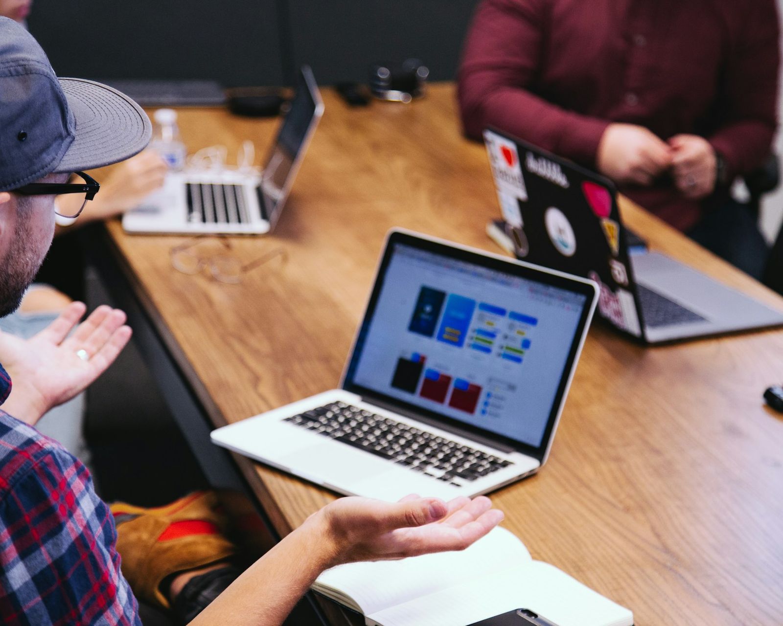 Management team around a meeting table with laptops showing charts, working through the numbers for a buyout