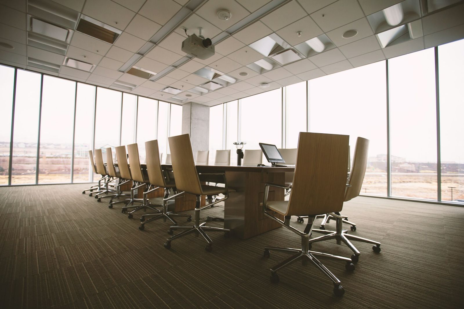 Empty oval boardroom table and chairs in a naturally lit meeting room