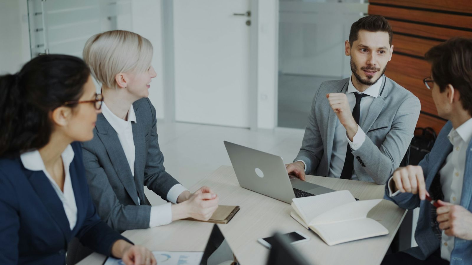 Four business people discussing financial charts around a meeting table